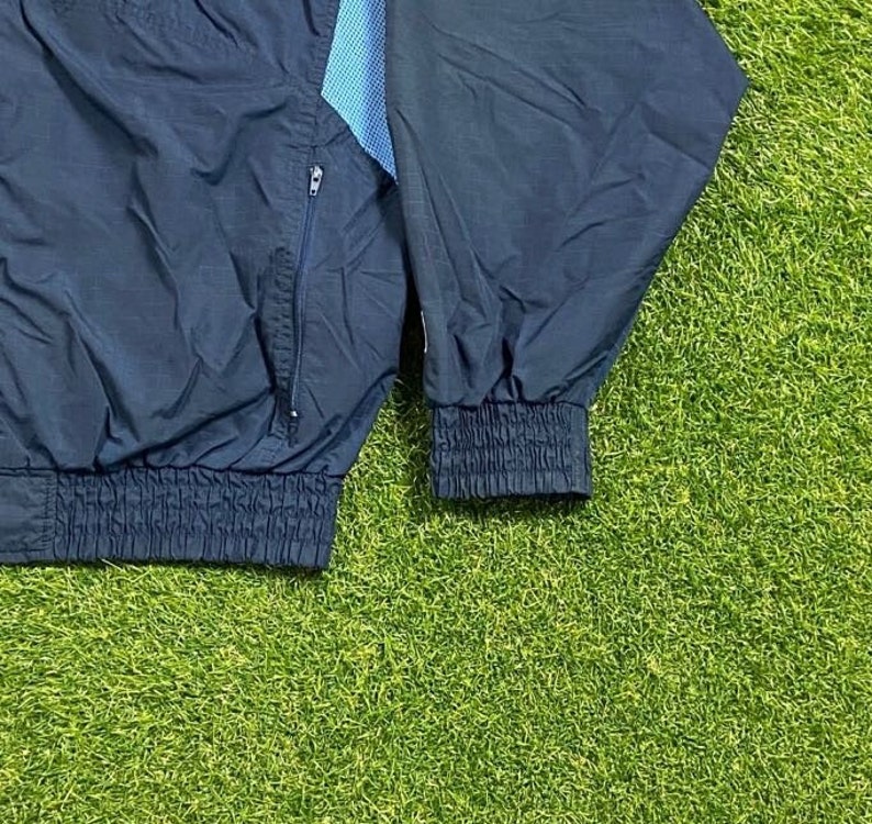 Peut inclure: Une veste coupe-vent bleu marine avec une fermeture &eacute;clair et une doublure &agrave; motifs bleu et blanc. La veste a une taille et des poignets c&ocirc;tel&eacute;s.