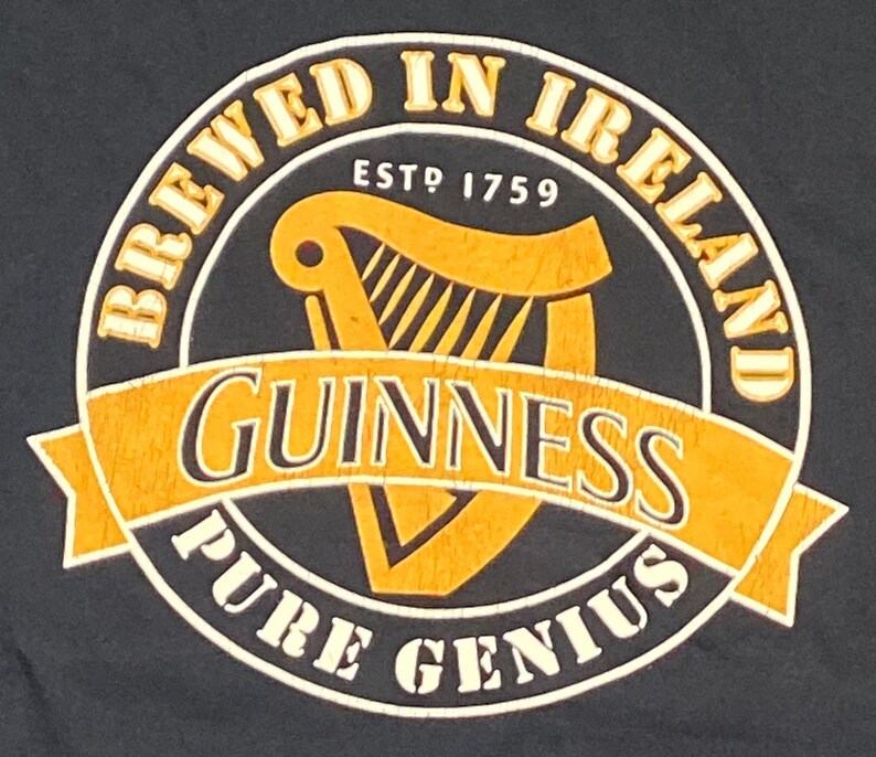 May include: A black and gold Guinness beer logo with the text "Brewed in Ireland" and "Est. 1759" around a harp. The text "Guinness" is in a large font and the text "Pure Genius" is in a smaller font.