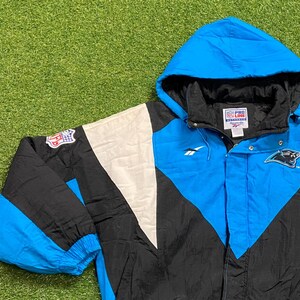 Peut inclure: Veste &agrave; capuche des Carolina Panthers en noir, blanc et bleu. La veste pr&eacute;sente le logo de l'&eacute;quipe, le logo NFL et la marque Reebok. Fermeture &eacute;clair compl&egrave;te et capuche.