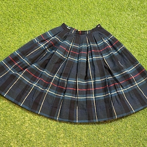 Può includere: Una gonna a pieghe blu e bianca a quadri. La gonna è realizzata in un tessuto leggero e ha uno stile semplice e classico.