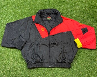 May include: A black and red windbreaker jacket with a zipper closure and a yellow accent on the sleeve. The jacket has a logo on the left chest and a pocket on the right sleeve.