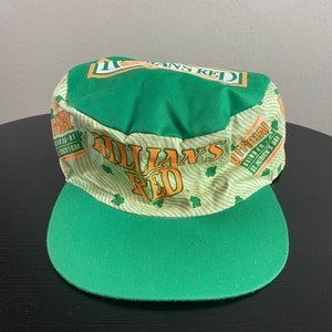 May include: Green and white baseball cap with the text "O'Dallan's Red" and "Official Drinker - St. Patrick's Day" printed on it.