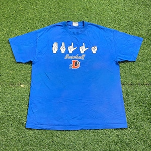 May include: A blue t-shirt with a crew neck. The shirt features white hand gestures above the word "Baseball" in blue script. Below the word "Baseball" is a red and orange letter "L" with a baseball design.