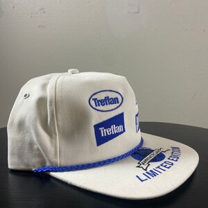 May include: White baseball cap with blue embroidered logos, including "Treflan" and "Anniversary Edition Limited Edition".