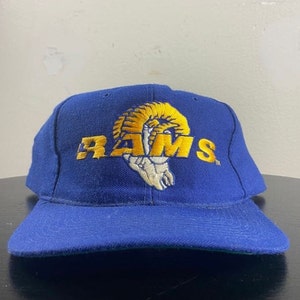 May include: A blue baseball cap with a yellow embroidered Rams logo featuring a ram's head and the word "RAMS".