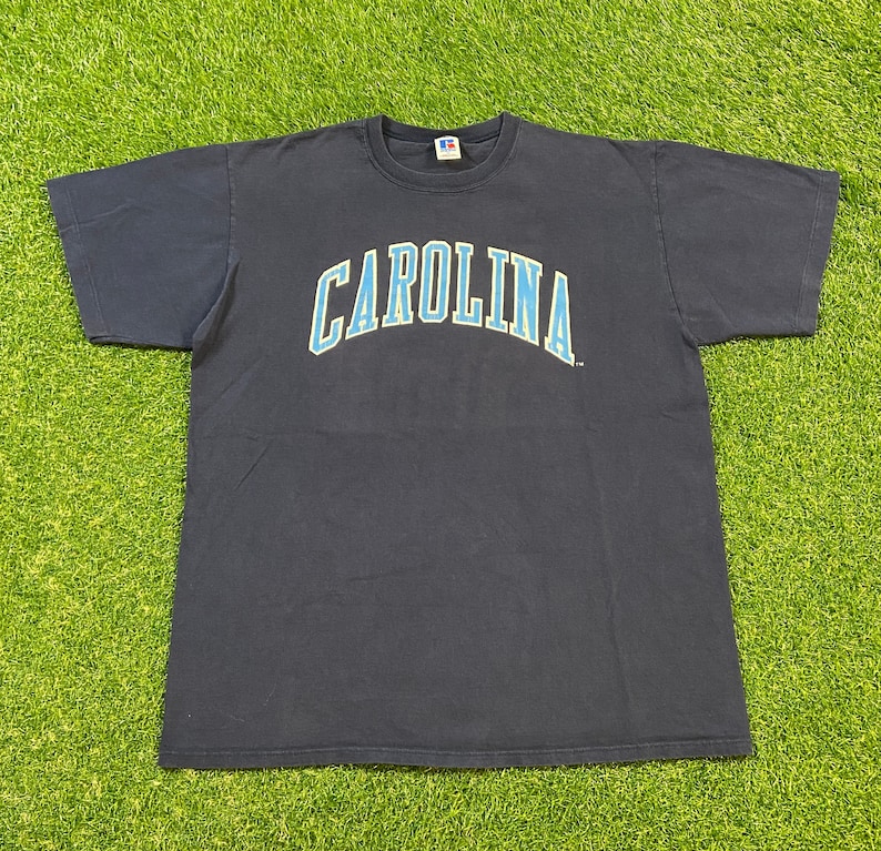 May include: A navy blue t-shirt with a light blue and yellow "CAROLINA" graphic on the front.