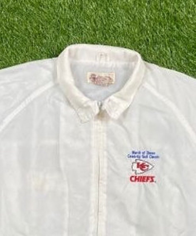 May include: White windbreaker jacket with a zipper closure and a red, white, and blue embroidered logo that says "Bank of America Community Self-Service Chiefs".