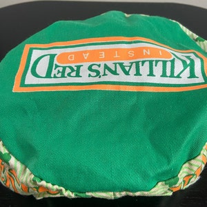 May include: Green and orange fabric hat with the text "Killians Red Instead" printed on the front.