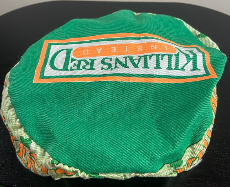 May include: Green and orange fabric hat with the text "Killians Red Instead" printed on the front.
