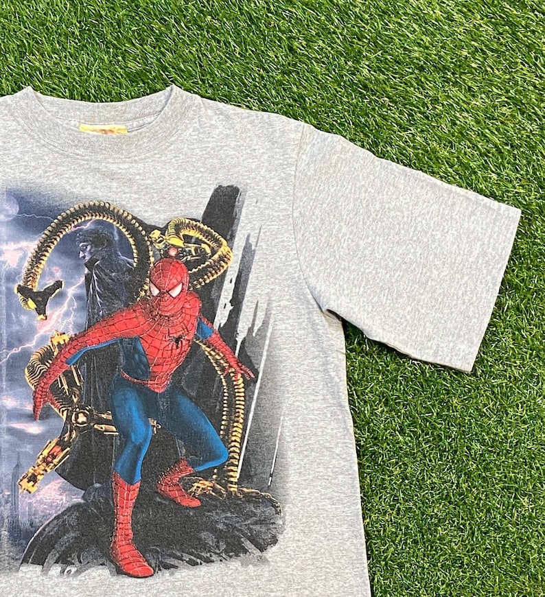 May include: Grey t-shirt featuring a graphic print of Spider-Man battling Doctor Octopus. The graphic is detailed and shows a dynamic pose of the two characters.
