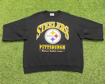 May include: A black long-sleeve sweatshirt featuring the yellow arched text Steelers above the Pittsburgh Steelers logo, which includes a circular emblem with yellow, red, and blue stars. Below the logo is the text Pittsburgh and National Football League.