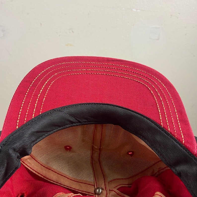 Op de afbeelding: Rode baseballpet met een zwarte rand en een beige mesh voering. De pet heeft een enkel stikseldetail rond de rand.