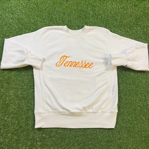 May include: White crewneck sweatshirt with the word "Tennessee" embroidered in orange on the front.