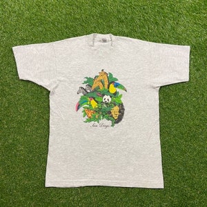May include: A gray t-shirt with a colorful graphic print of animals and the text "San Diego". The graphic features a zebra, a giraffe, a toucan, a panda, and a lion.