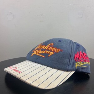 May include: A navy blue baseball cap with a white and navy pinstriped brim. The cap features the words "Yankees Racing" in yellow and red embroidery on the front and "MAC Tools Racing" on the side.