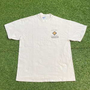 May include: A white short-sleeve t-shirt featuring a small graphic on the left chest. The graphic includes a diamond-shaped icon with the text MIPS RISC above it and the phrase The brains behind Windows NT printed in black lettering below.
