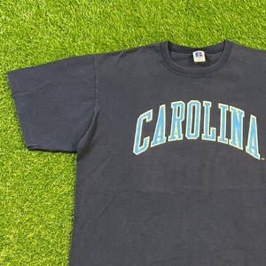 May include: A navy blue t-shirt with a light blue and white "CAROLINA" graphic on the front.