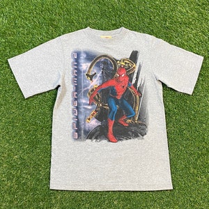 May include: A grey short-sleeved t-shirt with a graphic print of Spider-Man from the film Spider-Man 2. The graphic features Spider-Man fighting Doctor Octopus.