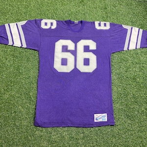 May include: Purple long-sleeved jersey with white stripes on the sleeves and a white number "66" on the front. The jersey has a Champion logo tag on the bottom right.