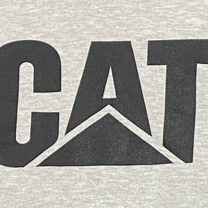 May include: Black and white logo of the word "CAT" with a black triangle in the center. The logo has a registered trademark symbol.