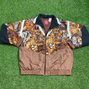 May include: A brown, black, and white patterned jacket with a zipper closure. The jacket features a variety of animal prints, including lions, tigers, and zebras.