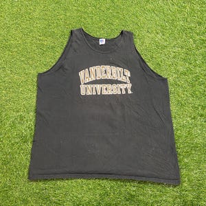 May include: Black tank top with the text "VANDERBILT UNIVERSITY" in gold lettering. The tank top is made of a soft material and is likely vintage. The tank top is laying on a green surface.