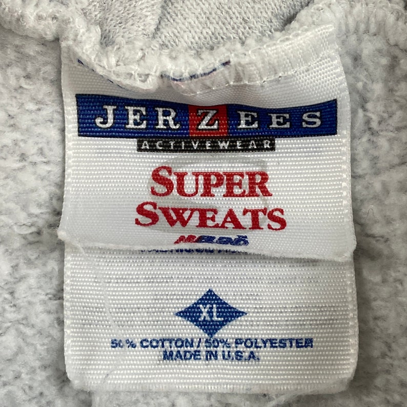 May include: A white tag with blue and red text that reads "JER ZEES ACTIVEWEAR SUPER SWEATS" and a blue diamond with the text "XL" and the text "50% COTTON/50% POLYESTER MADE IN U.S.A."