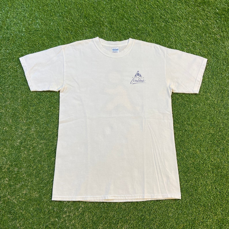Może przedstawiać: Biały t-shirt z niebiesko-szarym logo z napisem "America Online".
