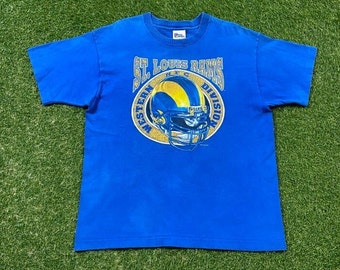 Op de afbeelding: Blauw T-shirt met een afbeelding van een St. Louis Rams helm en de tekst "St. Louis Rams Western NFC Division".