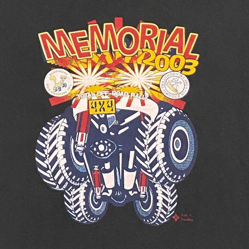 Może przedstawiać: Czarny T-shirt z kolorowym wzorem graficznym przedstawiającym kresk&oacute;wkowy samoch&oacute;d terenowy z tekstem "MEMORIAL 2003" i "TOTAL OFF-ROAD RALLY 4X4".