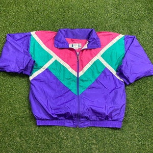 May include: A purple, pink, green and white windbreaker jacket with a zip closure. The jacket has a chevron pattern.