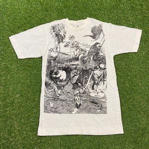 May include: White t-shirt with a black and white print of various Australian endangered species. The print includes a koala, a wombat, a bandicoot, a quoll, a sugar glider, and a cassowary. The text "AUSTRALIAN ENDANGERED SPECIES" is printed on the shirt.