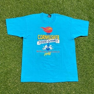 May include: A turquoise blue t-shirt with the text "Cornhusker State Games" and "Bowling Regionals 1992" in a colorful design. The graphic includes a torch and bowling pins.