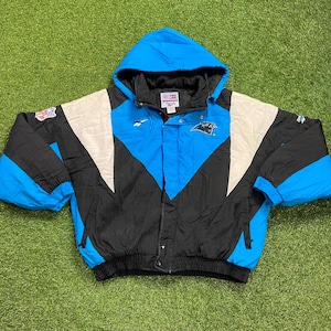 Peut inclure: Veste &agrave; capuche bleue, noire et blanche avec le logo des Panthers de la Caroline. La veste a une base noire avec des accents bleus et blancs, une fermeture &eacute;clair compl&egrave;te et une capuche. La veste est fabriqu&eacute;e par Reebok.