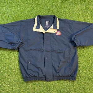 May include: A navy blue windbreaker jacket with a tan collar and a logo on the left chest. The logo is a colourful graphic of a building with the text "GEAR" above it.