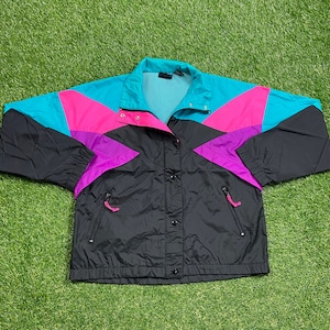 May include: A black, pink, teal, and purple color block windbreaker jacket. The jacket has a zipper closure and two pockets.