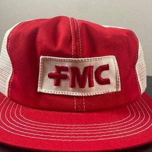 Può includere: Cappellino da camionista rosso e bianco con una toppa bianca che dice "FMC" in lettere ricamate rosse.