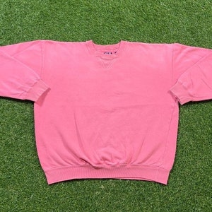 May include: A pink crew neck sweatshirt with long sleeves.