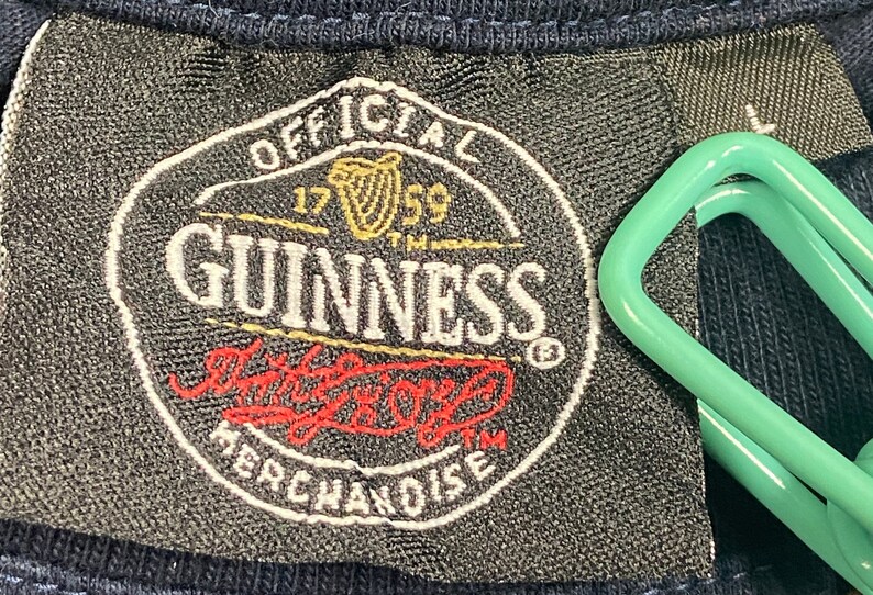 May include: Black and white label with the text "OFFICIAL 1759 GUINNESS" in a circle. The label also has a red and white logo with the text "The Original" and "MERCHANDISE" underneath.