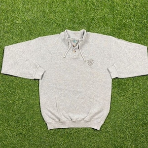 May include: A gray sweatshirt with a button-up collar and a small embroidered logo on the front.