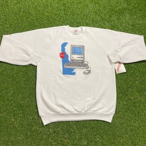 May include: White sweatshirt with a blue and white computer graphic and the text "MUD."  The computer graphic includes a red apple.