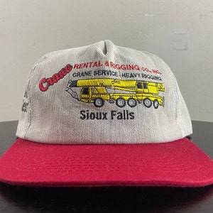 Könnte beinhalten: Eine graue und rote Baseballkappe mit einem gestickten Logo für Crane Rental & Rigging Co., Inc. Das Logo zeigt einen gelben Kran mit dem Text "Crane Service Heavy Rigging" und "Sioux Falls".