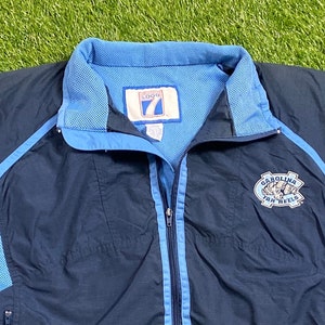Peut inclure: Une veste coupe-vent bleu marine avec des accents bleu clair et un logo Carolina Tar Heels sur le c&ocirc;t&eacute; droit. La veste a une fermeture &eacute;clair et une doublure en mesh.