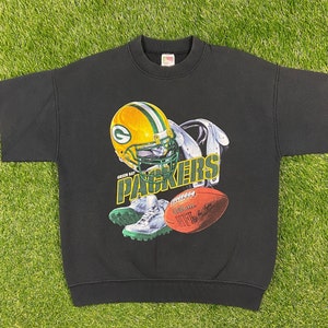 May include: Black short-sleeved sweatshirt with a green and yellow Green Bay Packers logo, a football, and the words "Green Bay Packers" printed on the front.