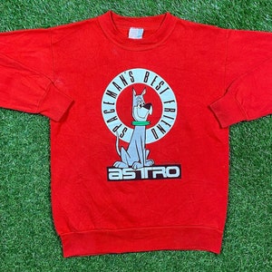 May include: Red long-sleeve sweatshirt with a cartoon dog graphic and the text "Spaceman's Best Friend" in a circle around the dog. The text "Astro" is printed below the graphic.