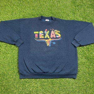 May include: A navy blue sweatshirt with a colorful graphic of a Texas longhorn and the word "TEXAS" in a colorful font.