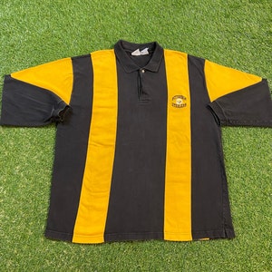 Könnte beinhalten: Langarm-Poloshirt mit schwarzen und gelben Streifen und dem gestickten Logo der Pittsburgh Steelers auf der Brust.