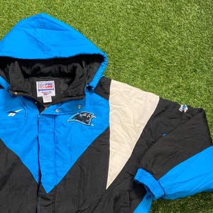 Peut inclure: Veste &agrave; capuche noire, blanche et bleu Carolina. La veste pr&eacute;sente le logo des Panthers de la Caroline sur la poitrine et les logos Pro Line et Reebok. La veste a une fermeture &eacute;clair compl&egrave;te et des poignets &eacute;lastiques.