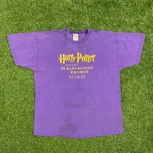 May include: Purple t-shirt with a yellow graphic that says "Harry Potter and the Half-Blood Prince 07.16.05".