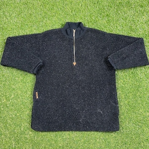 以下が含まれることがあります： 三角形のジッパーが付いた、黒いテクスチャのあるクォータージップセーターです。